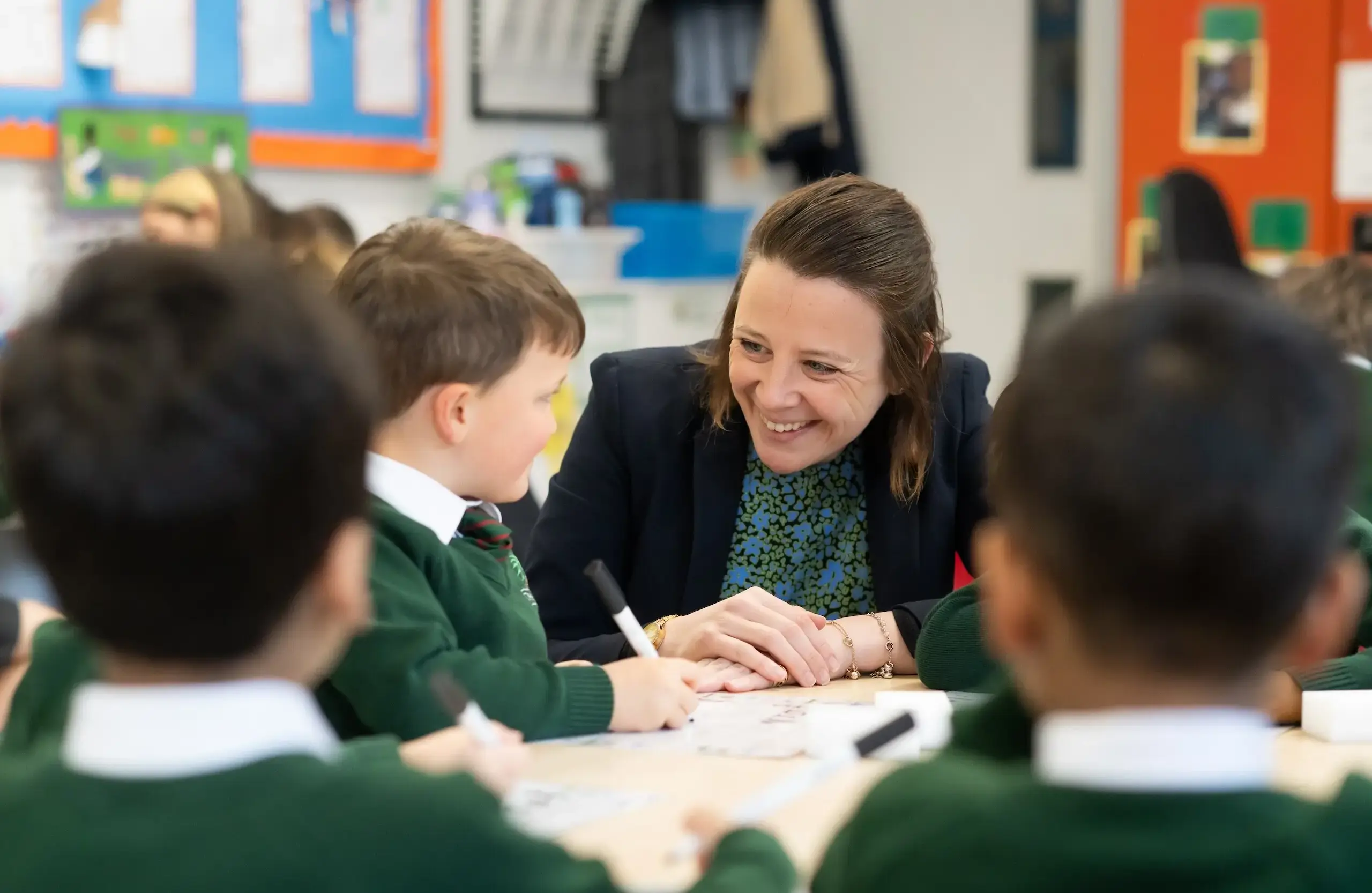 Teacher smiling at young student as they complete schoolwork