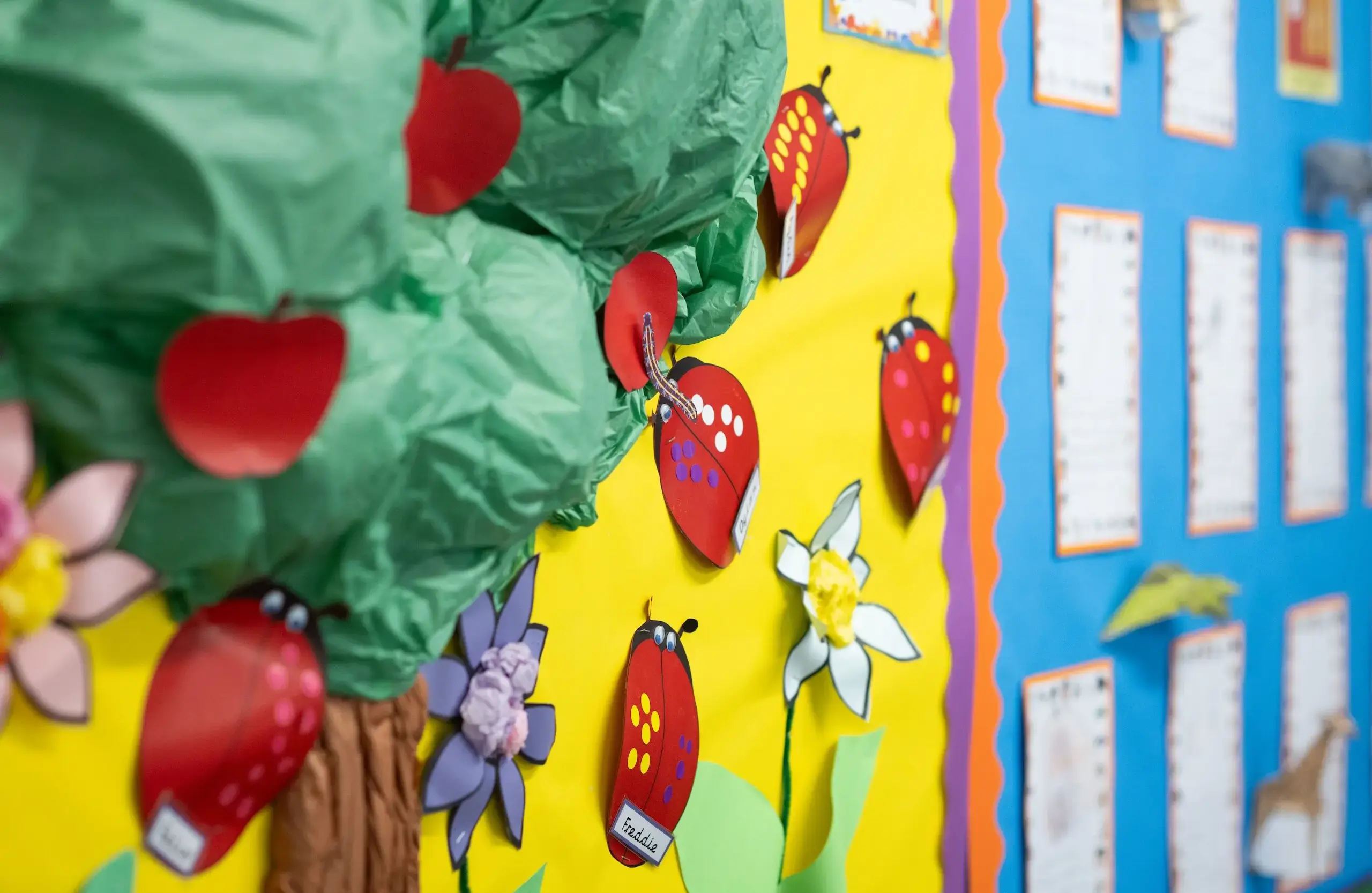 Wall adorned with crepe paper made to look like an apple tree with ladybirds flying around it