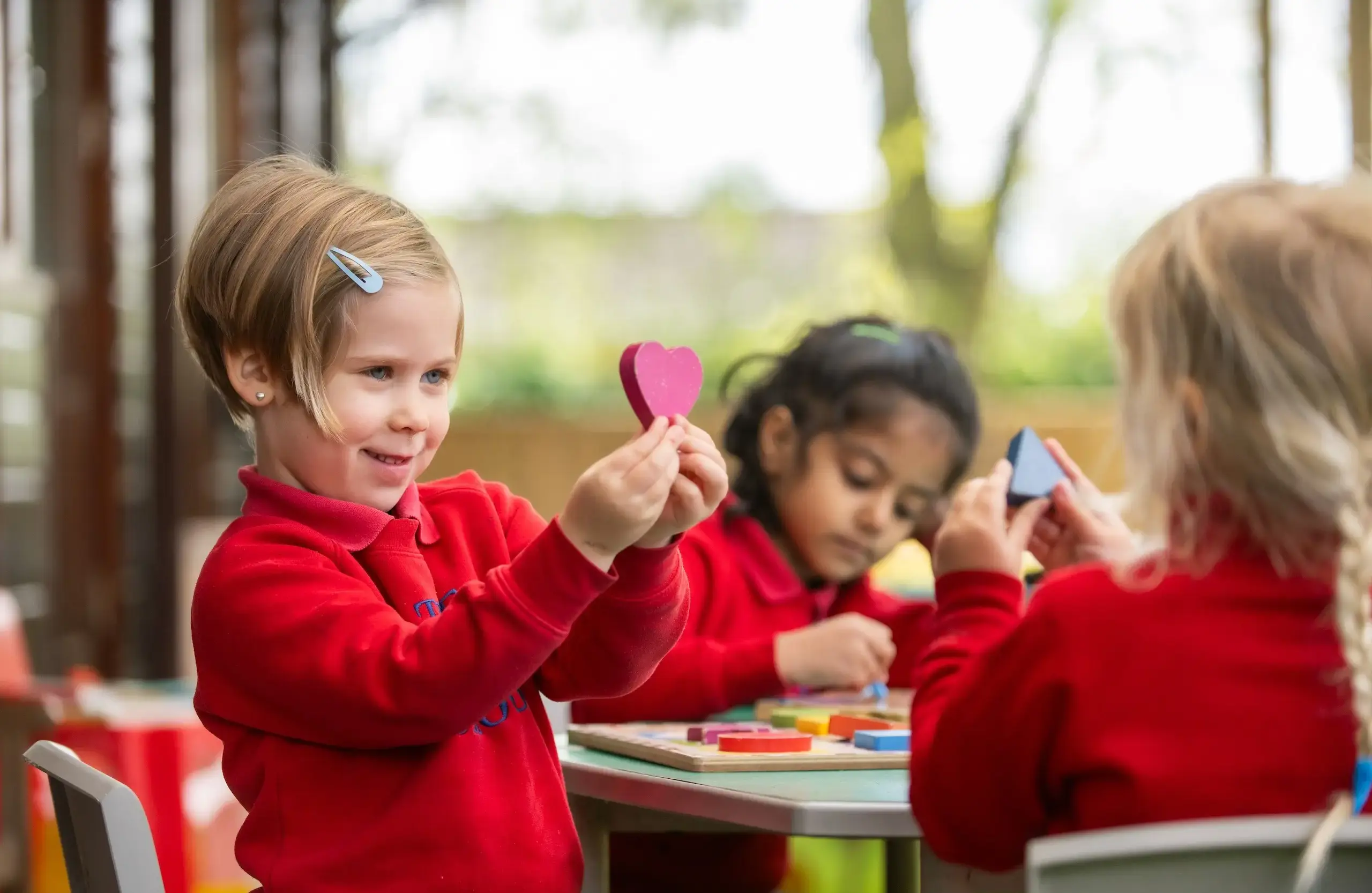 Student holding up a pink crafted heart