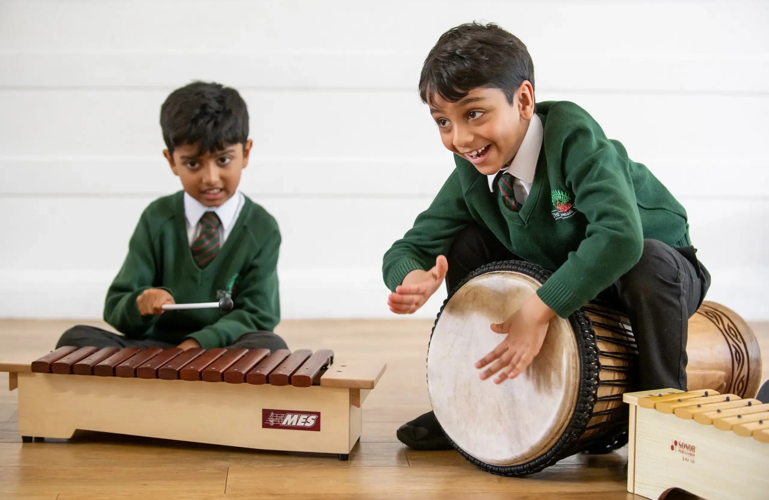 One boy playing a xylophone and another beating a drum