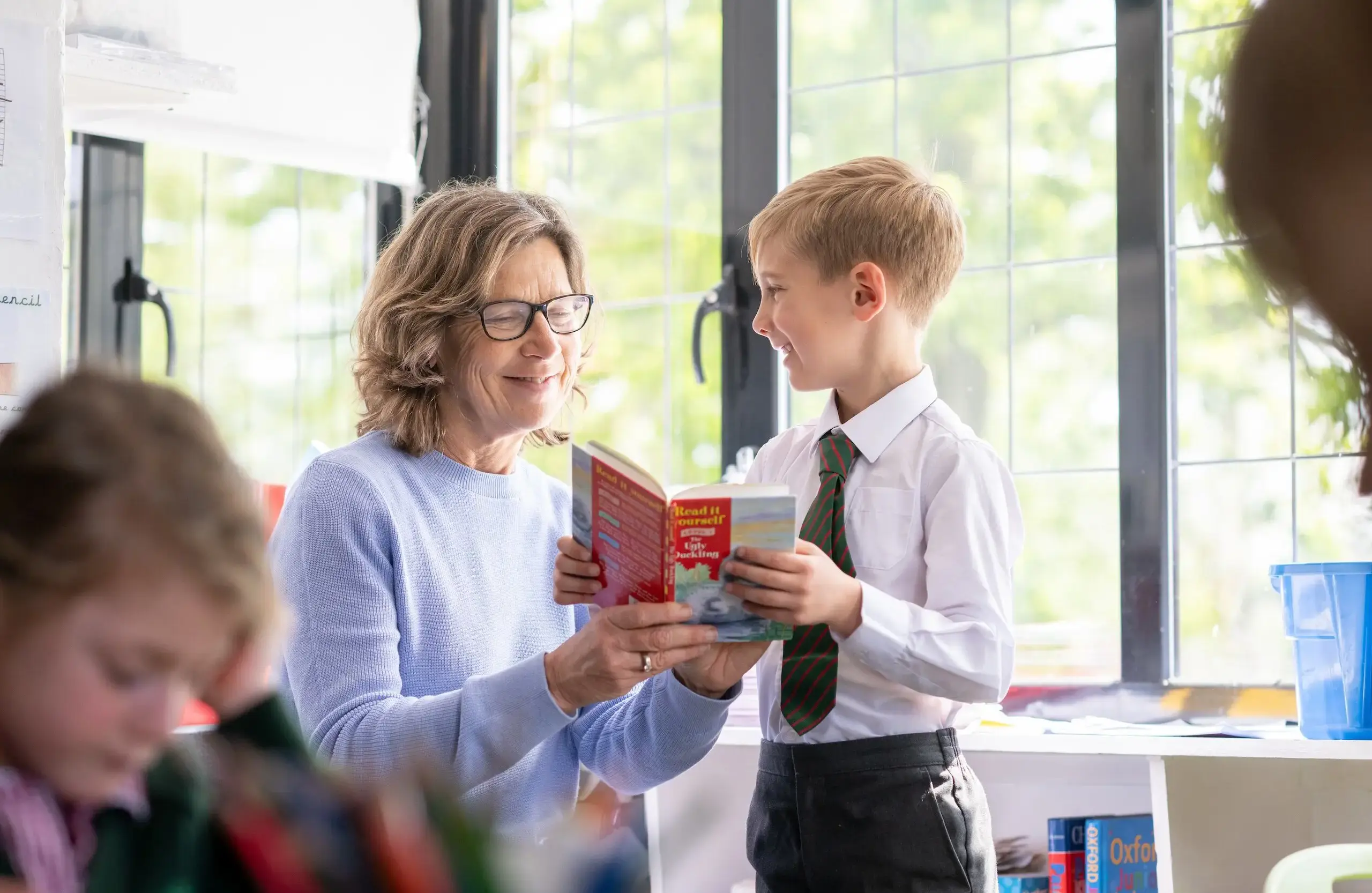 Teacher reading a book with a student