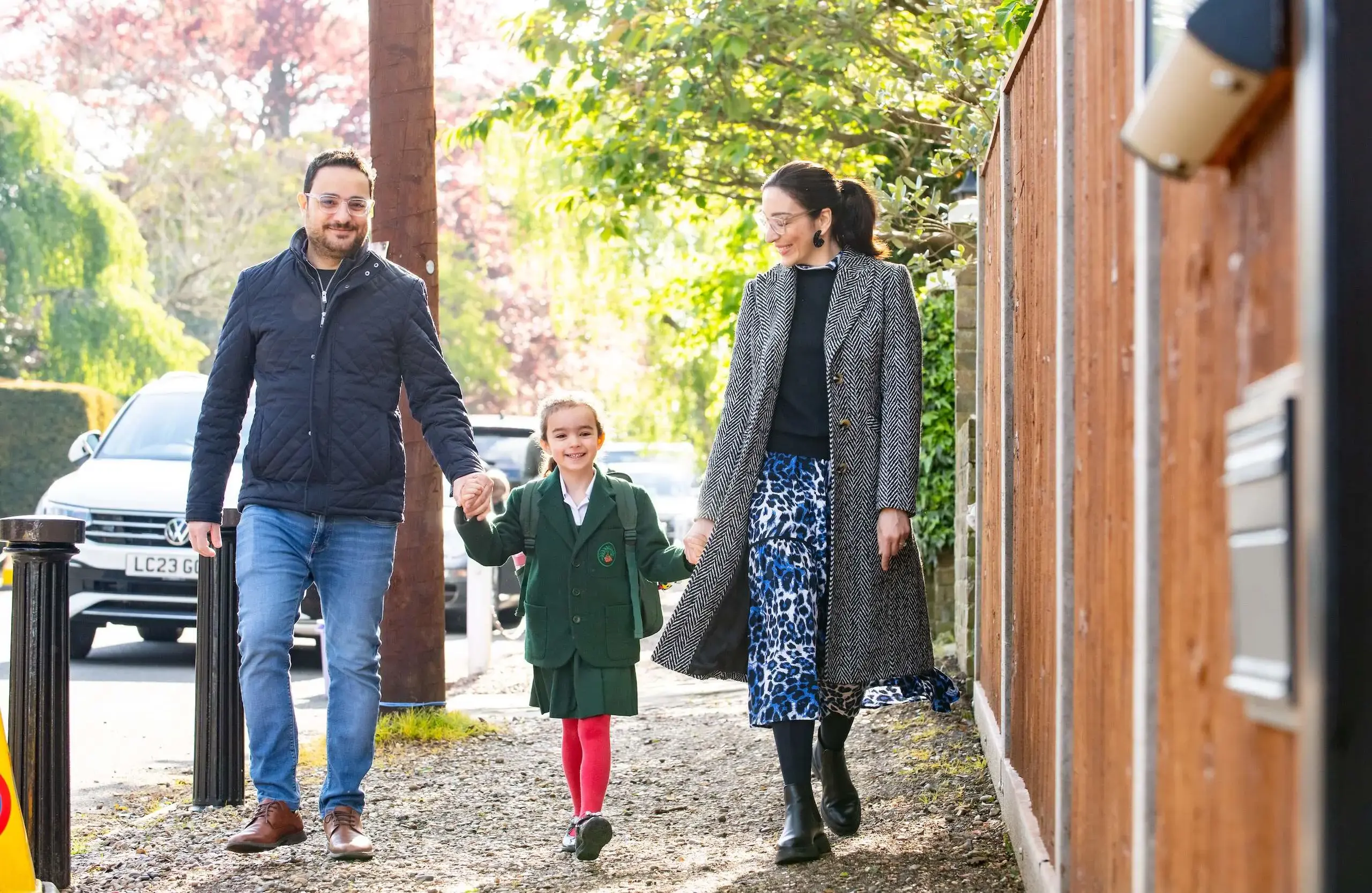 Two parents walking hand in hand with their daughter