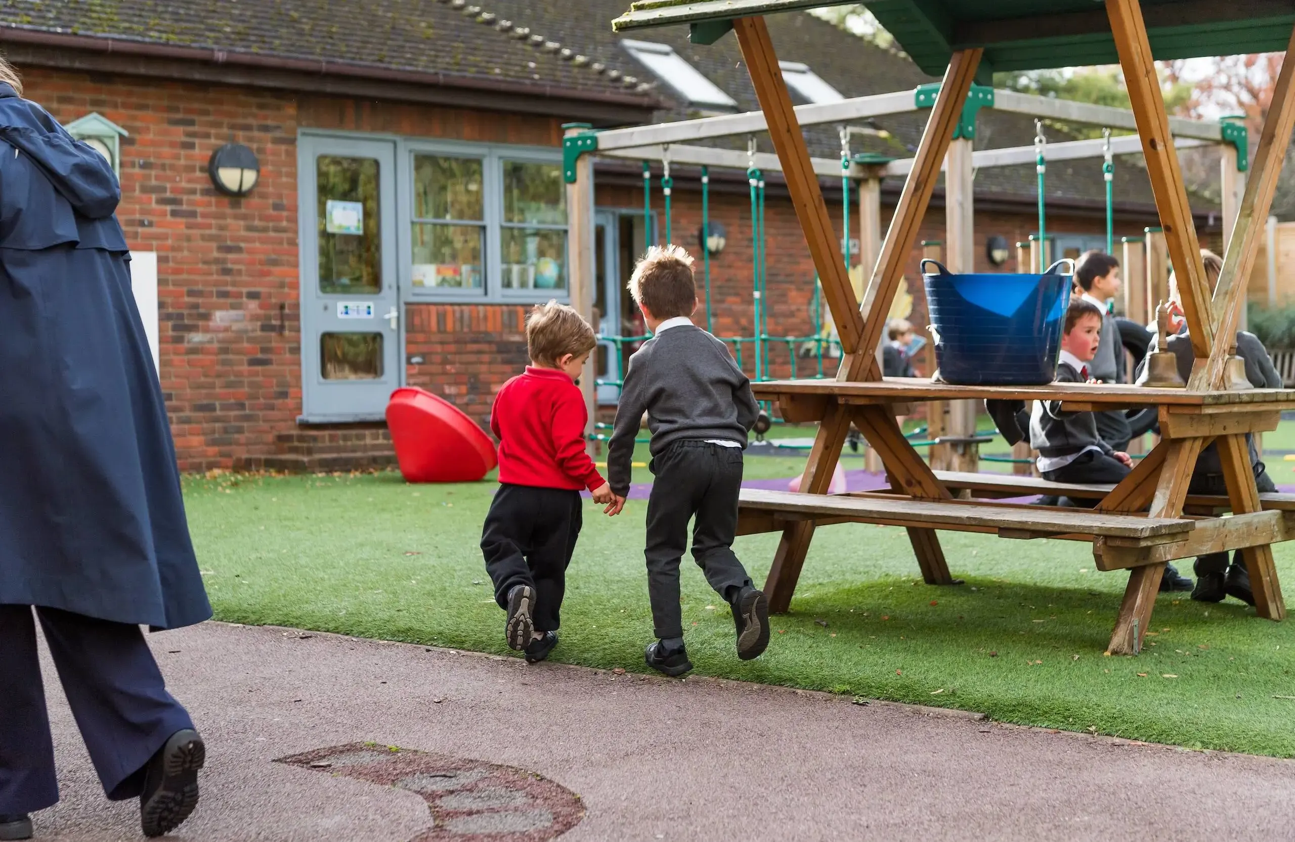 Two students running hand in hand past a picnic table