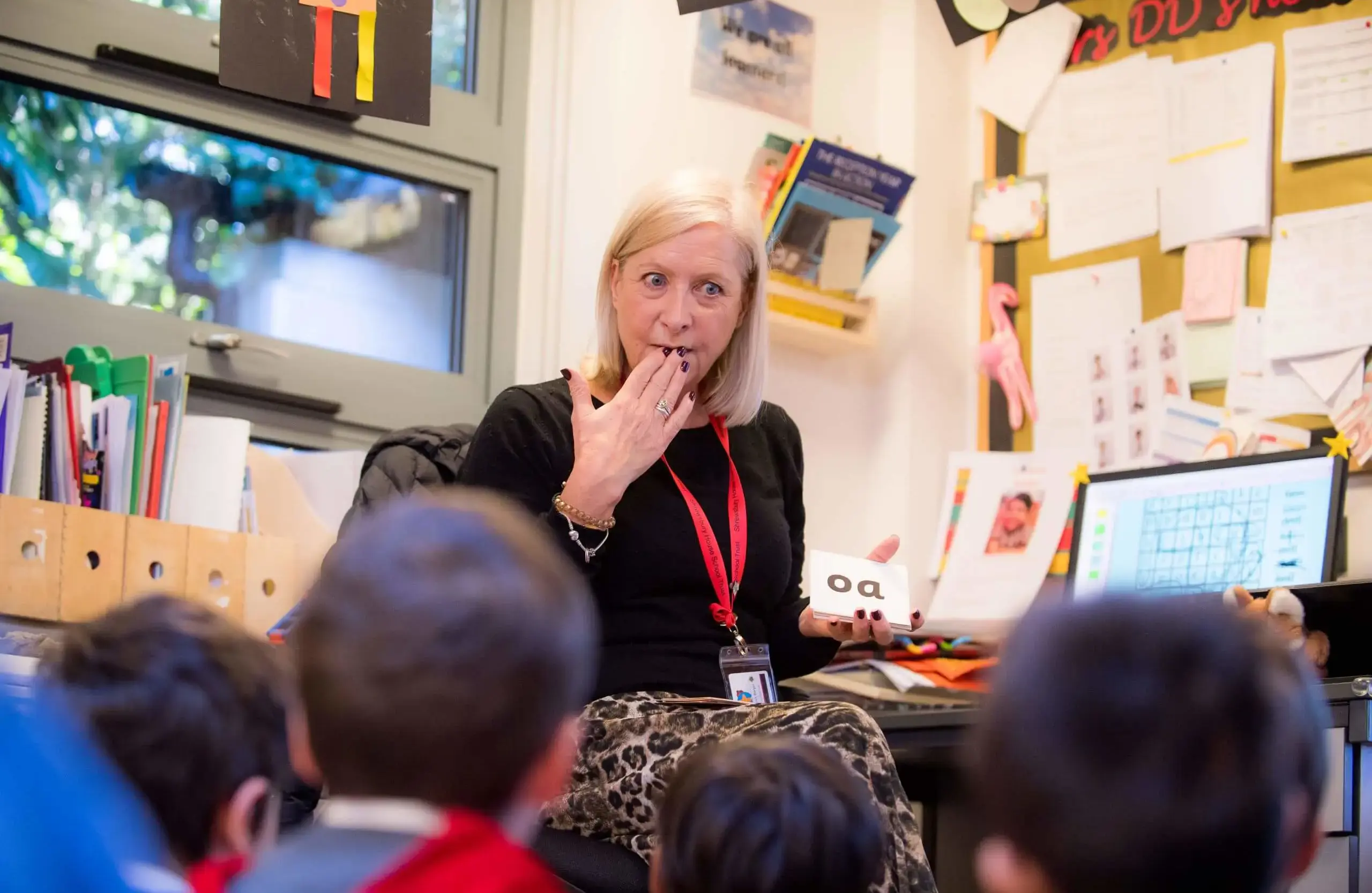 Teacher helping children to learn to read with flash cards