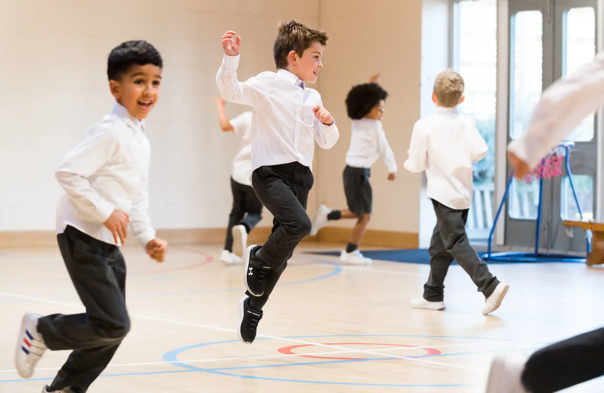 Shrewsbury House Pre-Prep students running and jumping in sports hall