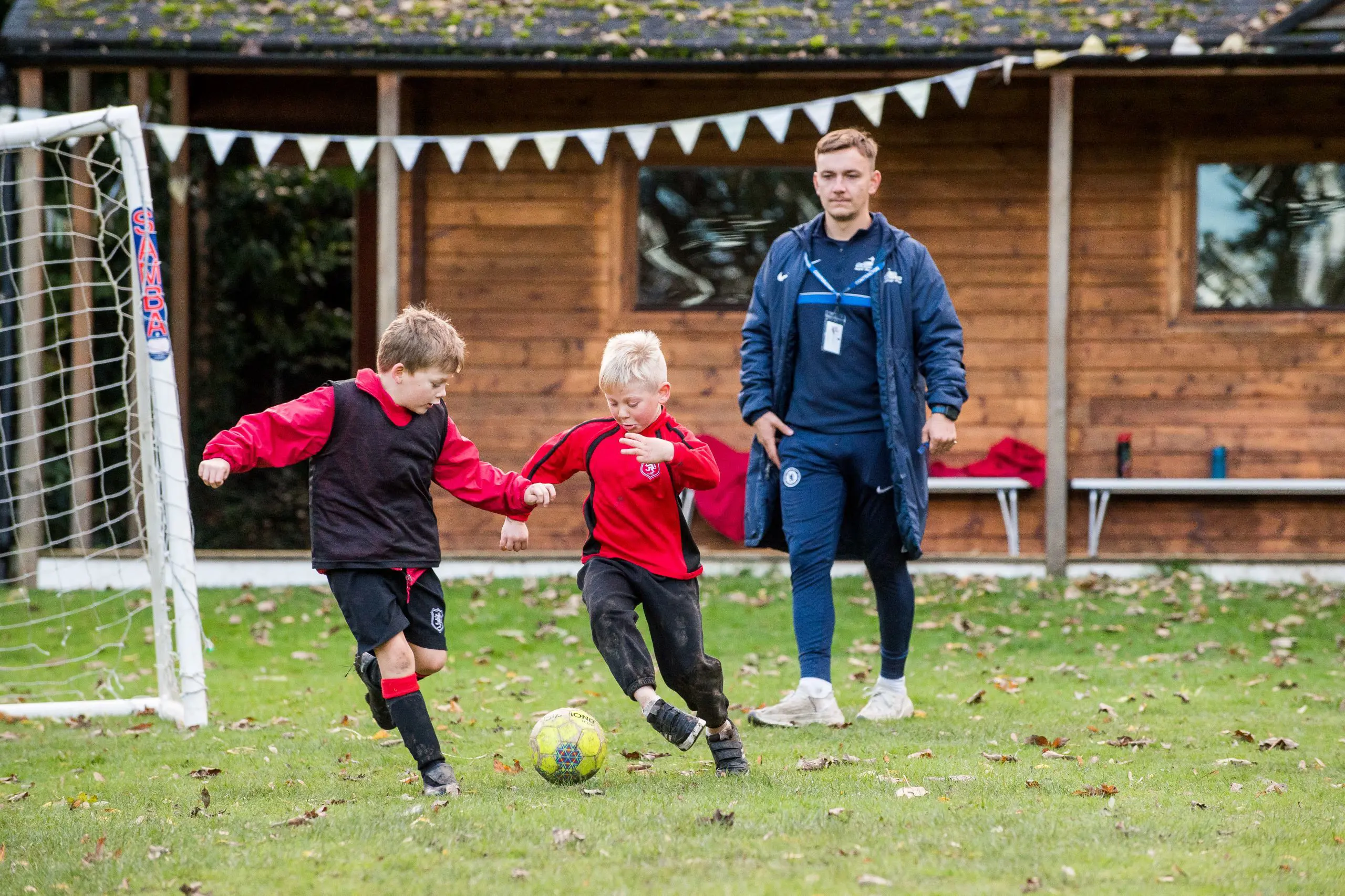 Shrewsbury House Pre-Prep Pupils playing football on the field with sports teacher supervising