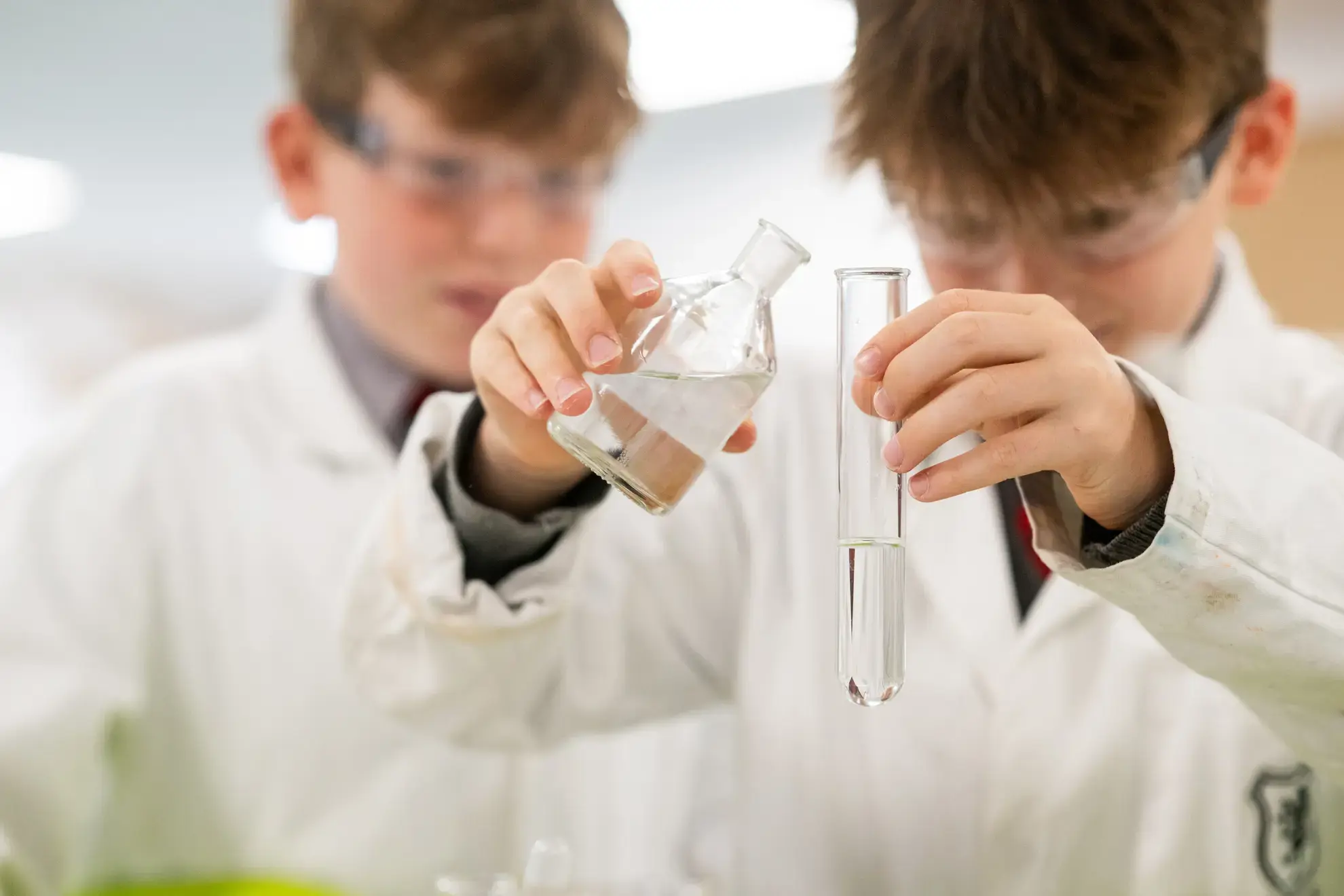 Students in lab coats mixing chemicals