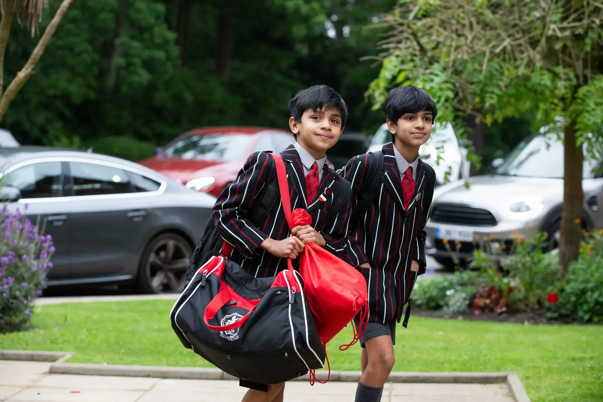 Two students walking, one carrying a large bag