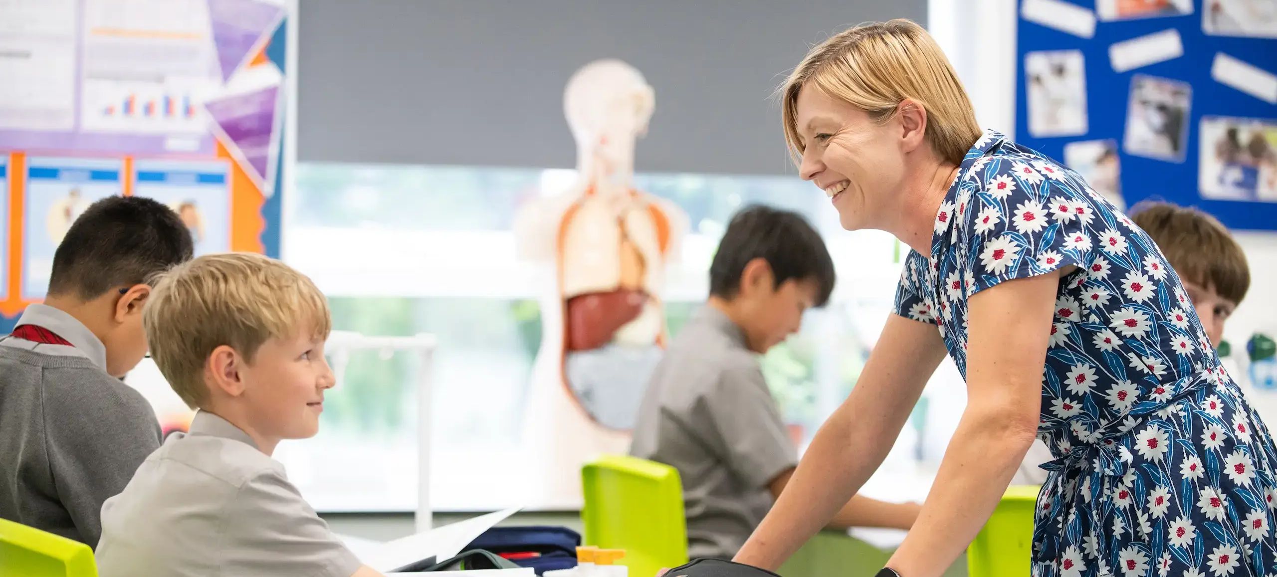 Teacher speaking to student in class in the midst of other students