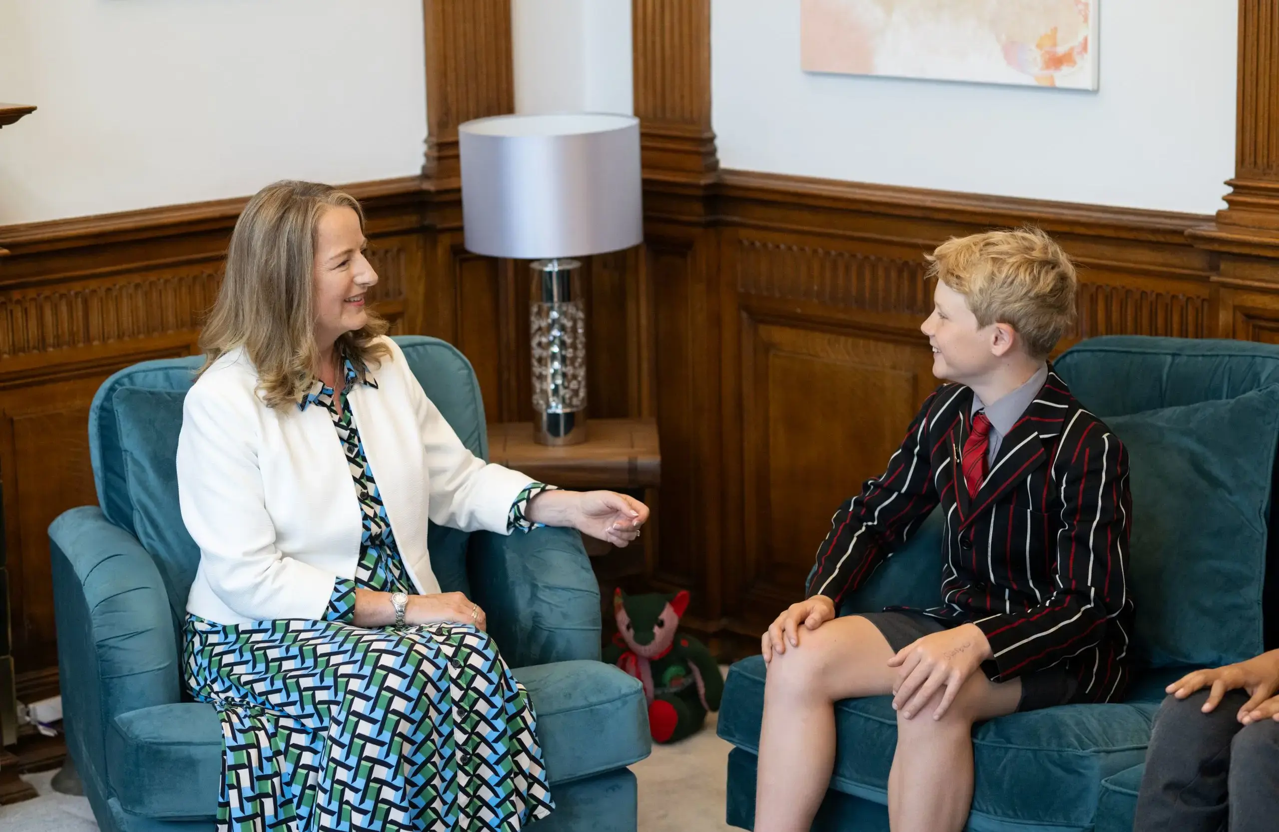 Teacher talking with one boy in uniform sitting on a sofa