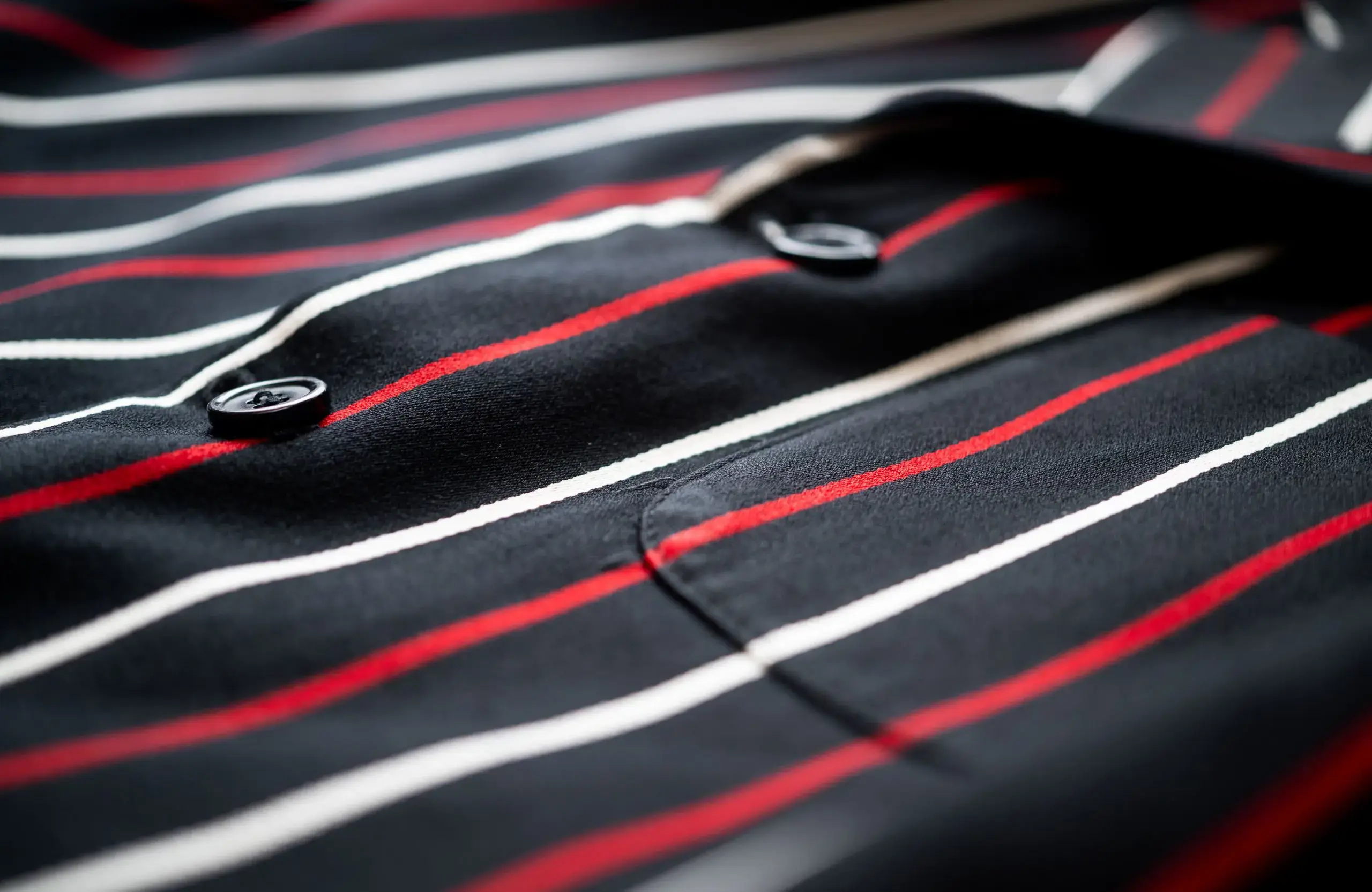 Close-up of a black blazer with red and white stripes and buttons.